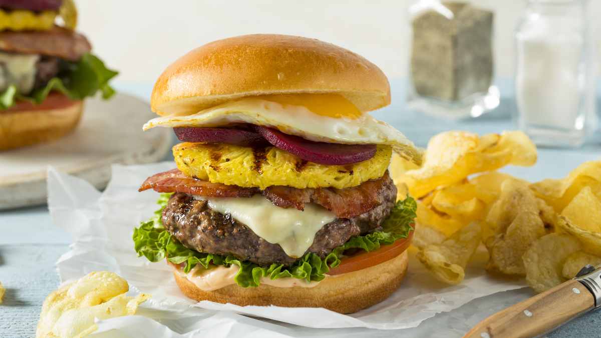 Hambúrguer australiano preparado no pão brioche com alface, tomate, carne de hambúguer, fatias de facon, uma rodela de abacaxi grelhado, rodelas de beterrba enlatada e um ovo frito.