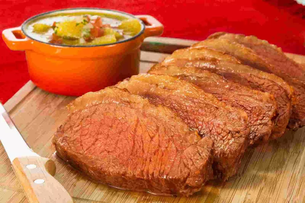 picanha na tabua com panela laranja ao lado 